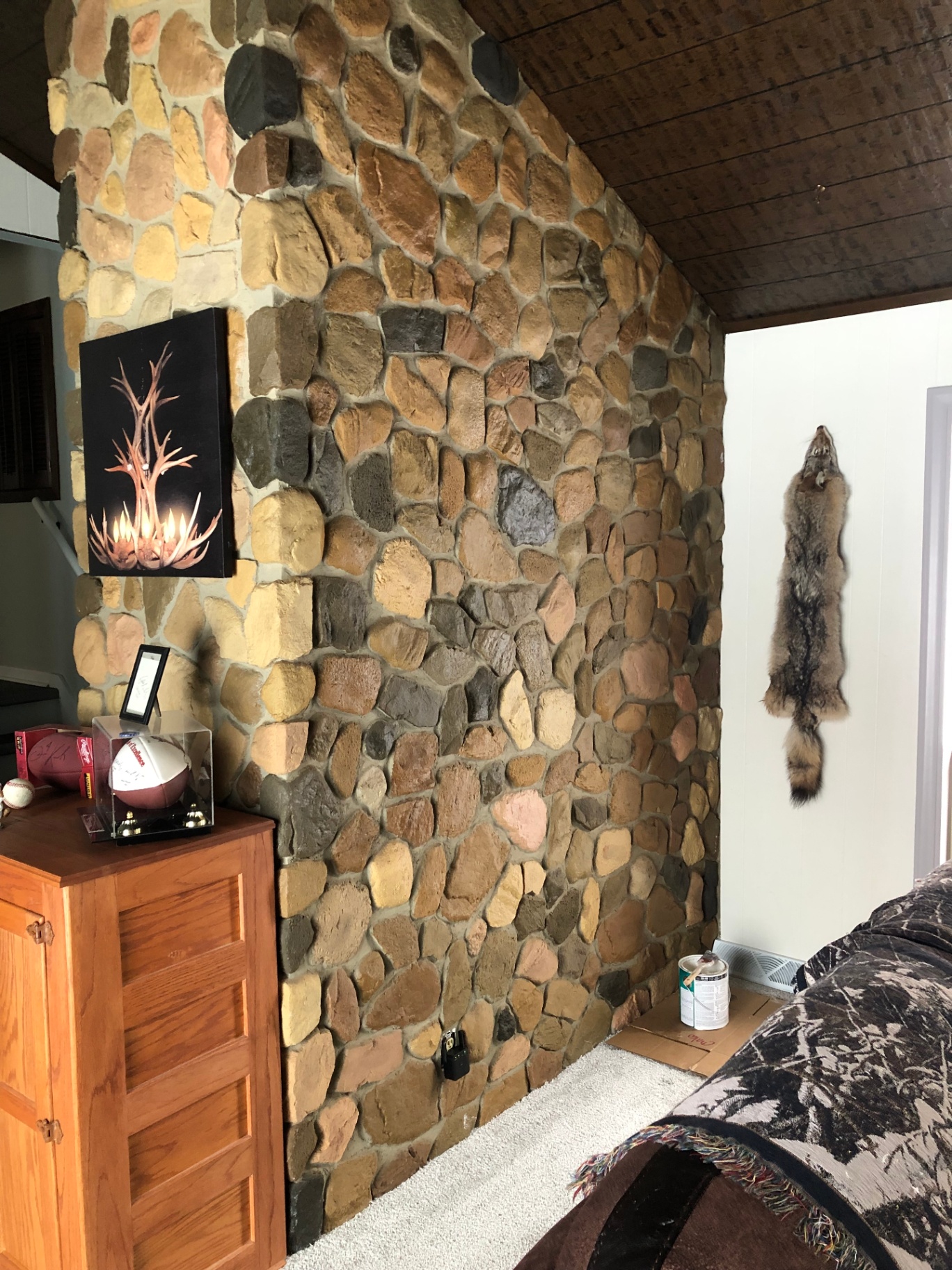 Original multi-tone interior stone accent wall in browns, tans, and grey next to a wood-paneled wall