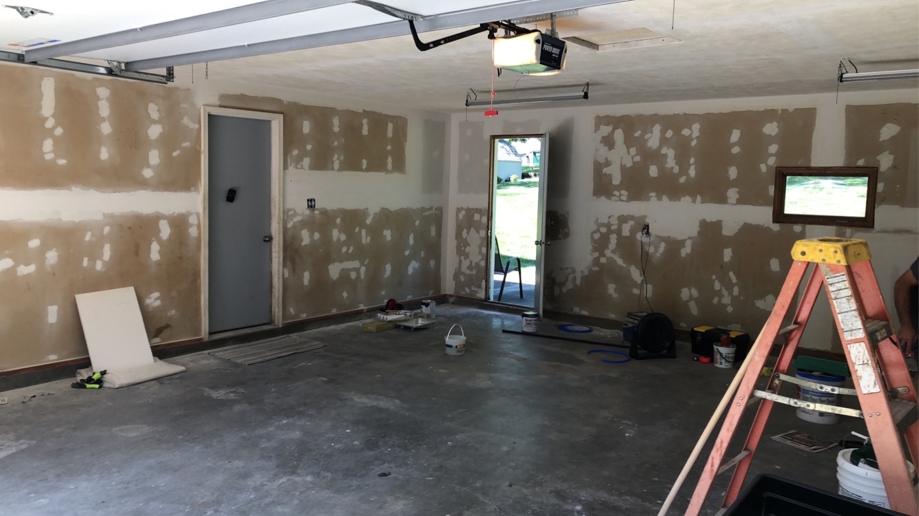 Garage interior with drywall walls covered in fresh joint compound patches, prepped and ready for primer and paint