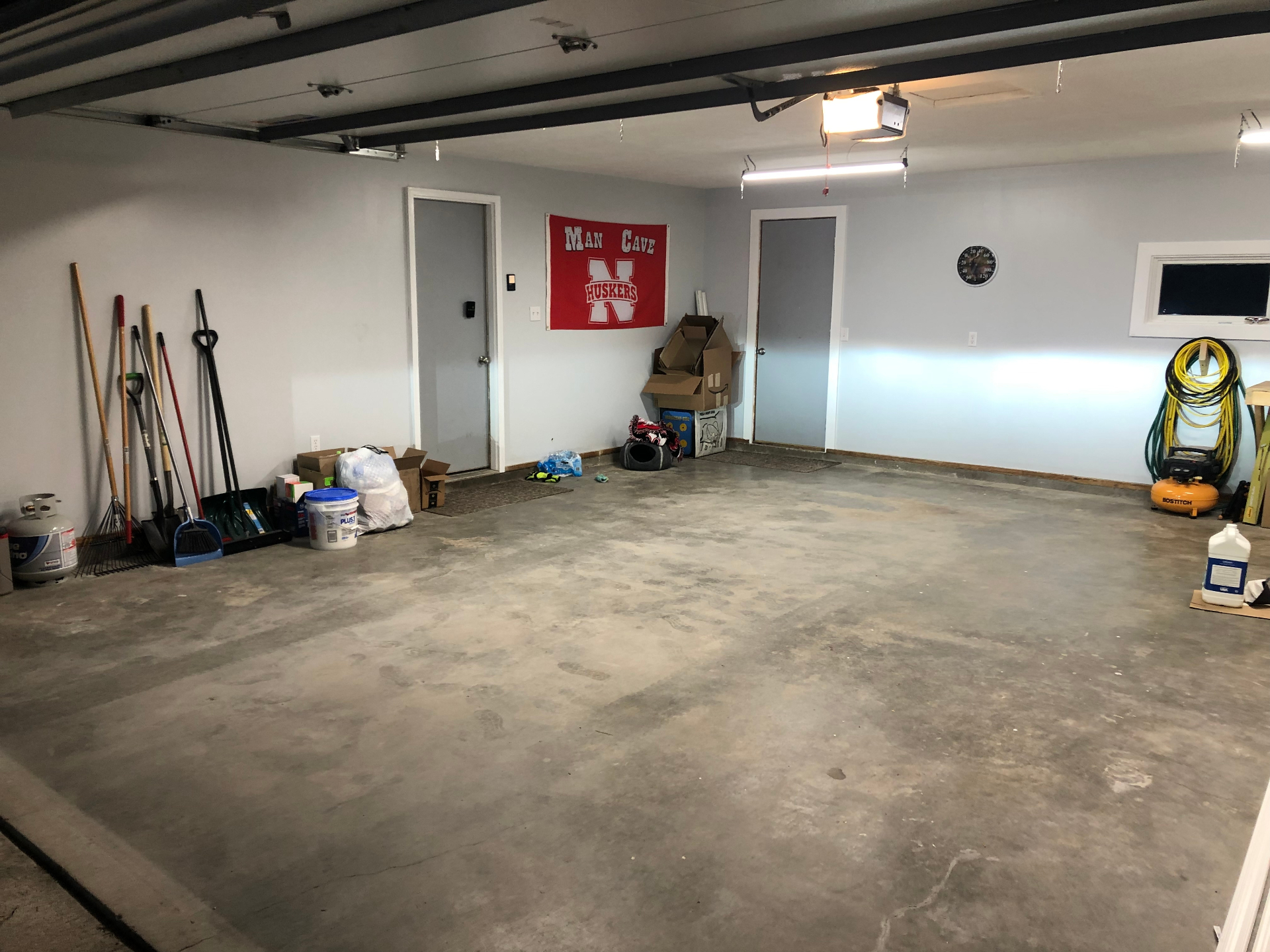 Clean, empty two-car garage with tools lined up along one wall and open floor space after a cleanout