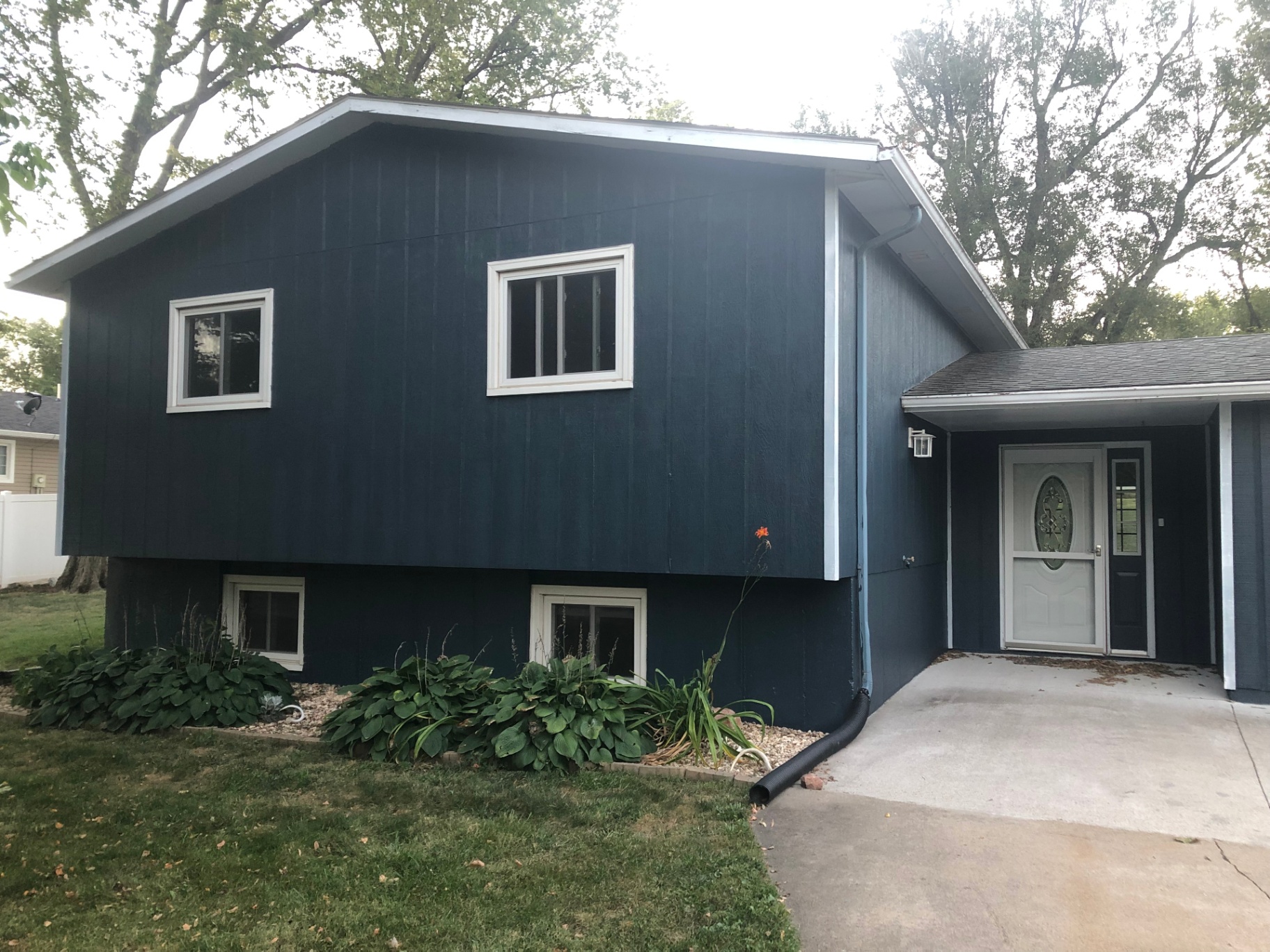 Two-story split-level home exterior repainted a deep navy blue with crisp white window trim and clean foundation paint